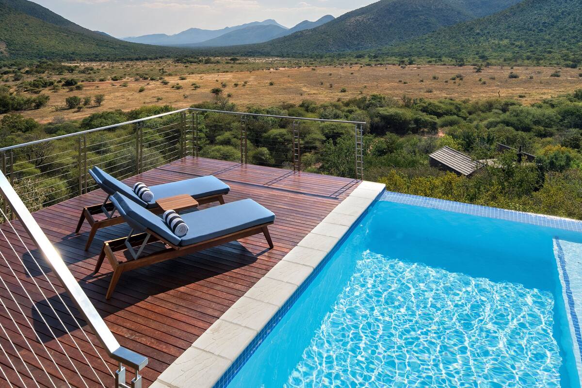 A poolside area with lounge chairs and a view of a mountainous landscape.