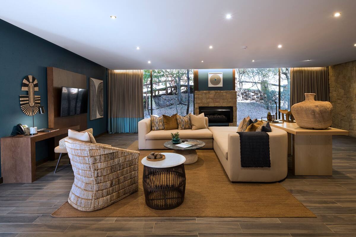 A modern living room with a stone fireplace, comfortable seating, and a large window overlooking a natural landscape.