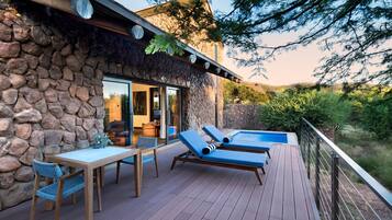 A stone exterior with a deck, a pool, and lounge chairs.