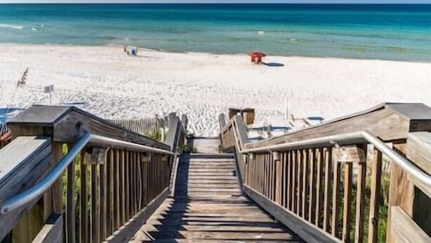 Un escalier en bois mène à une plage d’où l’on a une vue dégagée sur l’océan.