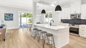 Une cuisine moderne dotée d’un grand îlot central, de tabourets de bar et d’appareils électroménagers en acier inoxydable.