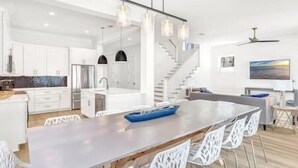 Une cuisine moderne dotée d’un îlot central, de meubles blancs et d’un escalier menant à un niveau supérieur.
