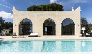 Un edificio con tres ventanales arqueados y una piscina delantera.