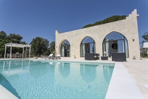 A swimming pool with lounge chairs and a building with arched windows. - Interior Designed "Mini Castle" with Pool in Puglia (Francavilla Fontana)