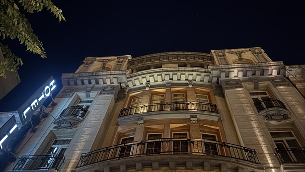 A grand building with multiple balconies and arched windows, illuminated at night. - HOTEL ILISIA (Thessaloniki)