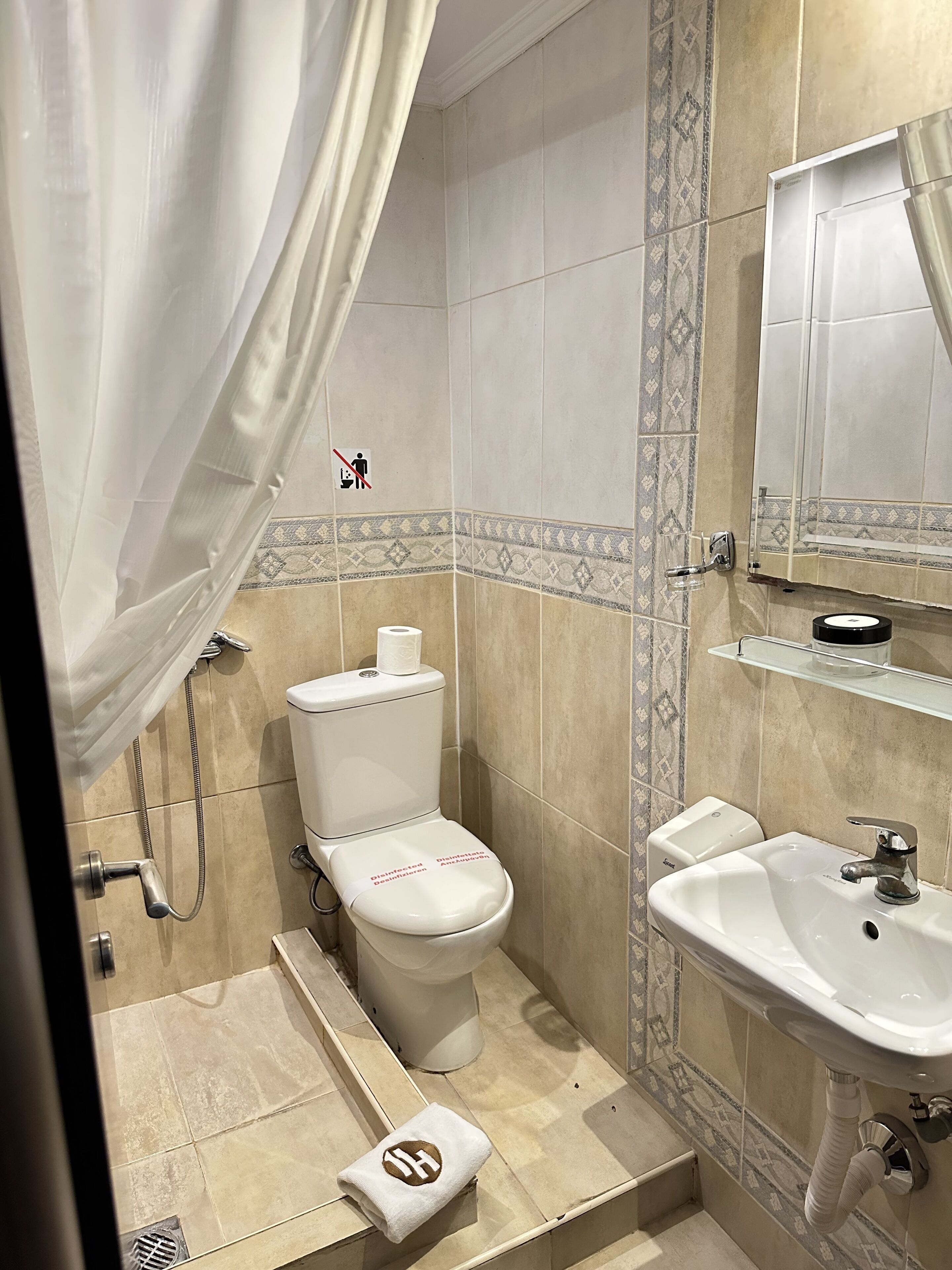 A bathroom with a toilet, sink, shower, and a towel rack.