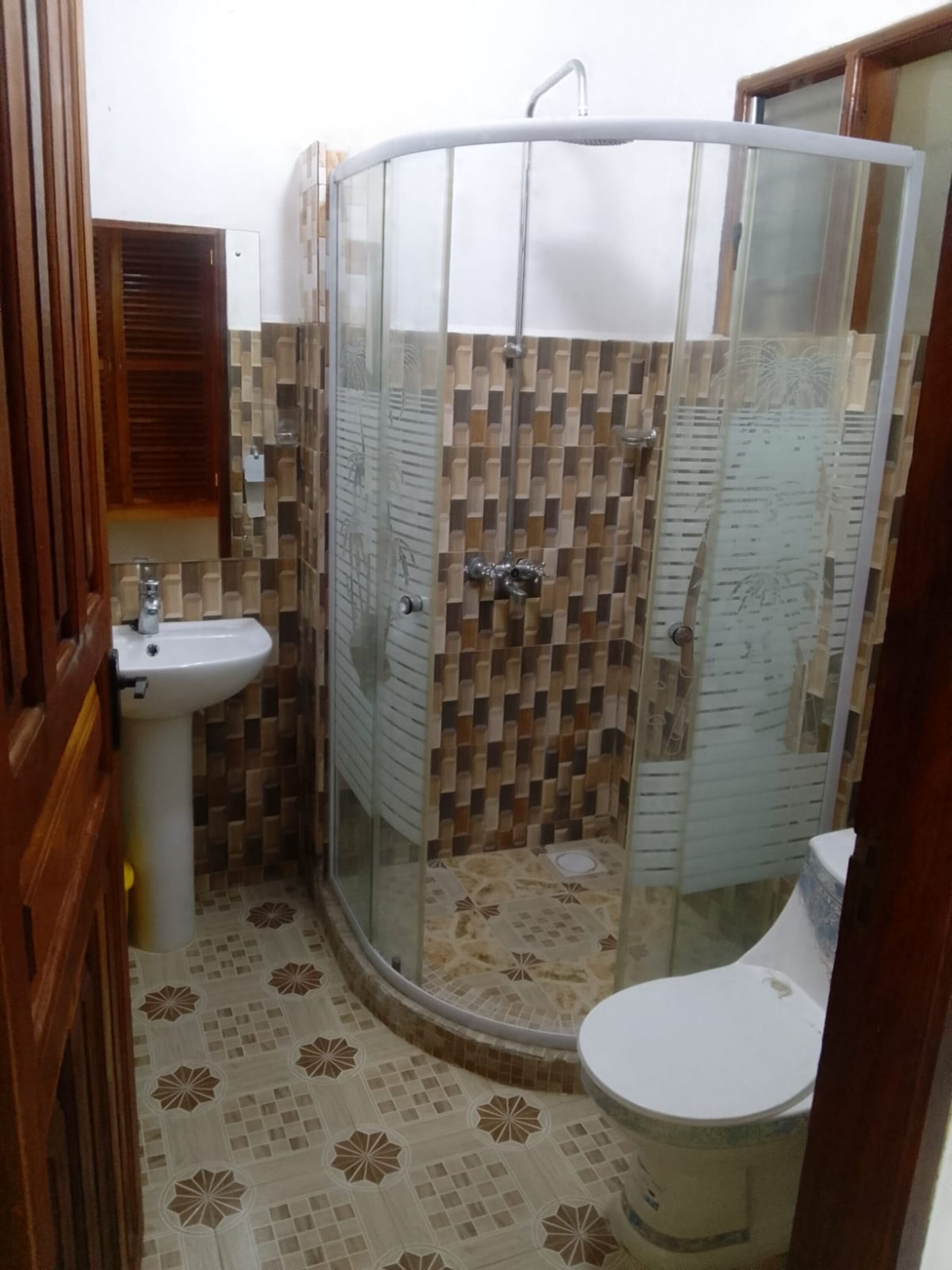 Um banheiro com chuveiro em box, pia e vaso sanitário.