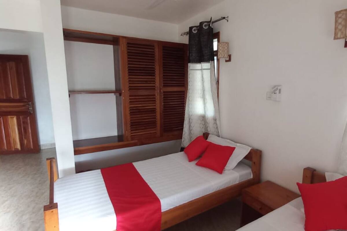 Un dormitorio con cama, armario de madera y ventana con contraventanas.