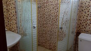 Un baño con ducha de vidrio, inodoro y lavabo.