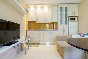 Una cocina compacta con armarios blancos, un comedor con mesa y sillas, y un sofá.