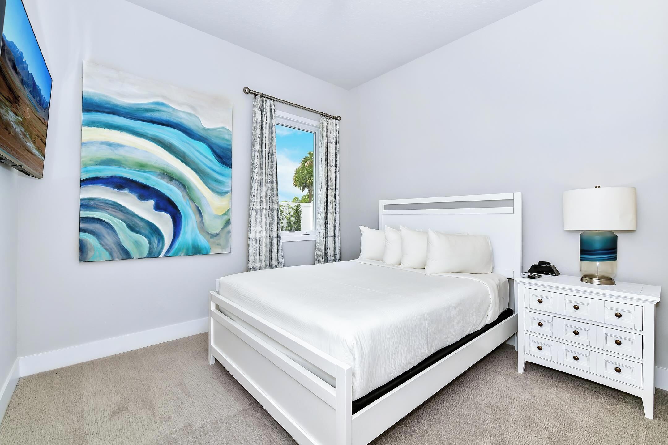 A bedroom with a bed, a nightstand, a lamp, and a painting on the wall.