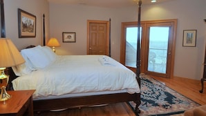 A bedroom with a four-poster bed, a ceiling fan, a nightstand with a lamp, and a large window with blinds. - Redbud Keep - move theater, wifi, golf, view, recreation center access, grill (Hedgesville)