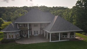 A large two-story house with a covered patio, a separate garage, and a landscaped lawn. - Redbud Keep - move theater, wifi, golf, view, recreation center access, grill (Hedgesville)