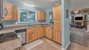 Een moderne keuken met houten kastjes, granieten aanrecht en een ingebouwde vaatwasser.