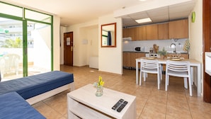 A compact living space with a kitchenette, a dining area, and a bedroom with a sofa. - FESTIVAL VILLAGE APARTMENTS (Salou)