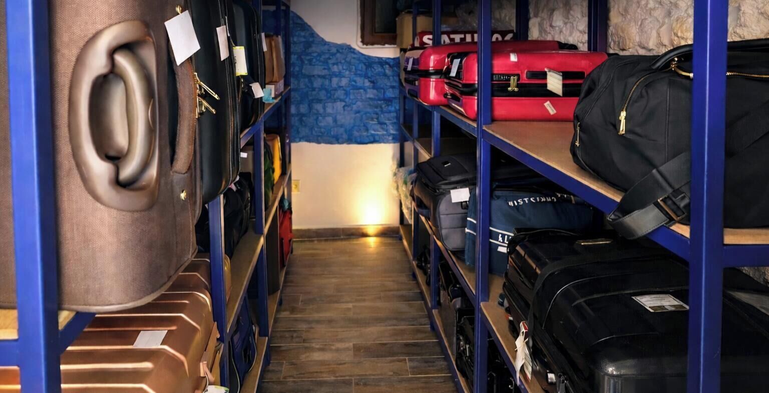 Un área de almacenamiento con estanterías llenas de maletas y bolsos, una pared azul y un piso de madera.