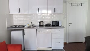 Eine kompakte Küche mit weißen Schränken, einer Mikrowelle, einer Kaffeemaschine und einem Geschirrspüler.