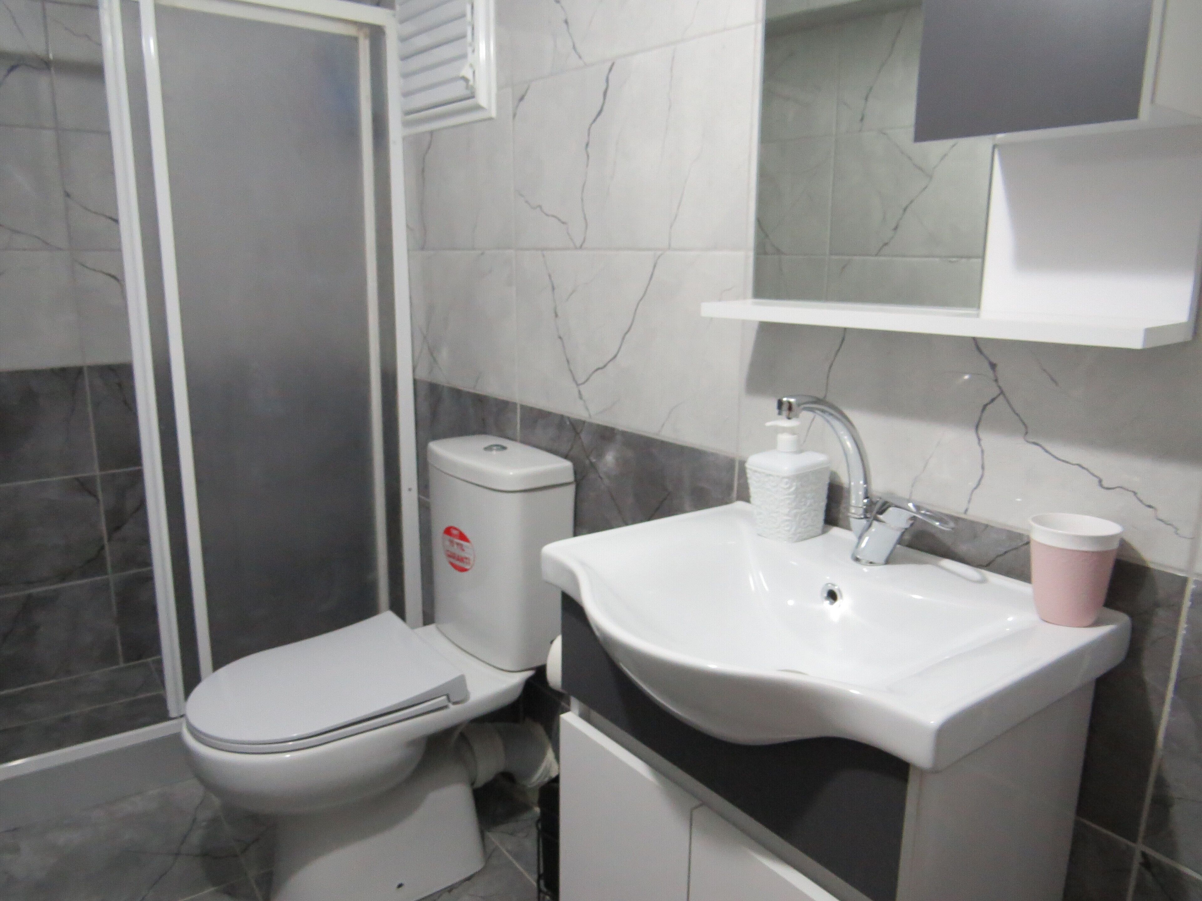 A bathroom with a toilet, sink, and shower.