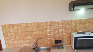 A kitchen with a sink, stove, and microwave. - Georgias House Project Ground Floor (Skiathos)