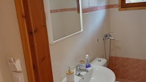 A bathroom with a sink, toilet, and mirror. - Georgias House Project Ground Floor (Skiathos)