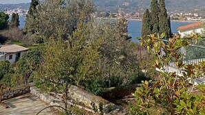 A coastal view with a stone pathway leading to a building, surrounded by trees and a clear sky. - Georgias House Project Ground Floor (Skiathos)
