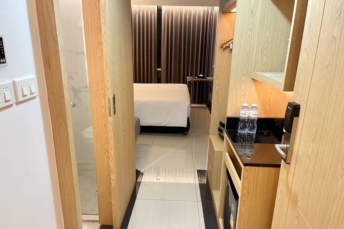 Una habitación de hotel con una cama, un escritorio pequeño con un espejo y un dispensador de agua.