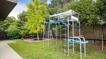 A playground with a climbing structure and swings.