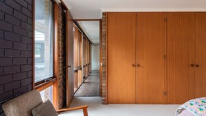 Un corridoio con parete in mattoni, porte in legno e un divano.
