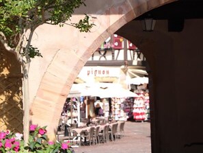 An outdoor café area with tables and chairs under a stone archway. - Charming Apartment with Terrace near Colmar City Center (Colmar)