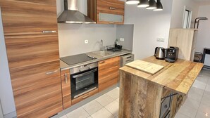A modern kitchen with wooden cabinets, stainless steel appliances, and pendant lighting.