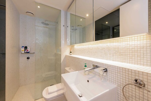 A modern bathroom with a glass-enclosed shower, a white sink, and a toilet. - 2-bed in South Melbourne w/ Beautiful City Views (South Melbourne)