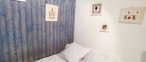 A bedroom with a wooden headboard, a bed with white bedding, and three framed pictures on the wall.
