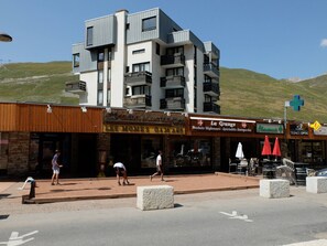 Um edifício de vários andares com um restaurante chamado "Les Mômes Oa16 ANS" e uma farmácia.