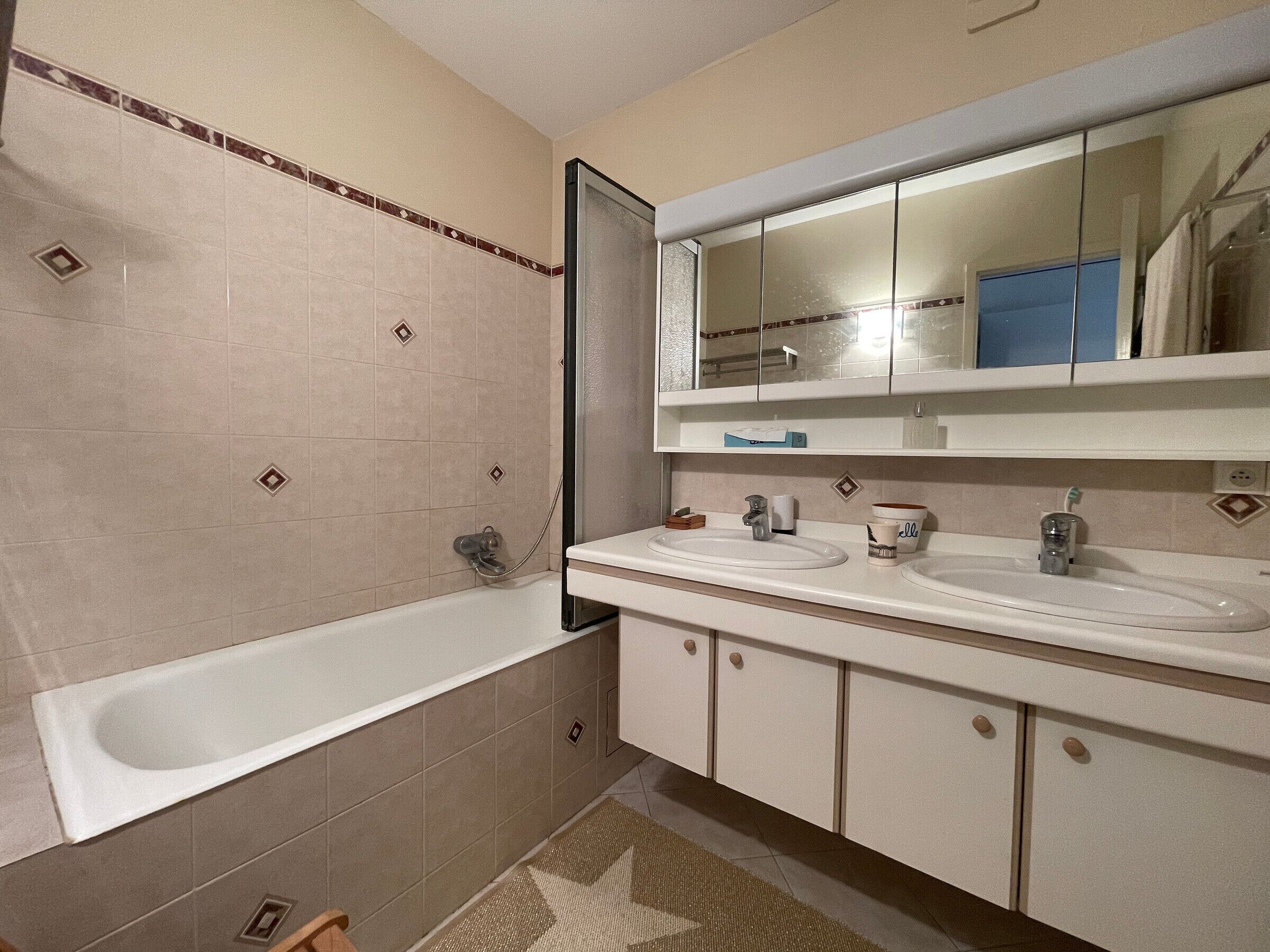 Un baño con bañera, dos lavamanos, un espejo y ducha.