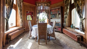 A room with a wooden floor, a round table with chairs, a bookshelf, and a window with curtains. - Luxury Spa Castle With Swimming Pool (Jalhay)