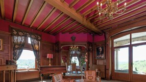 A grand room with a piano, a table, and chairs, a chandelier, and large windows with a view. - Luxury Spa Castle With Swimming Pool (Jalhay)