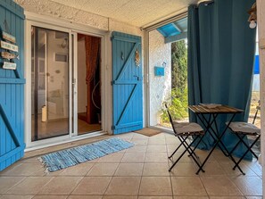 Ein Zimmer mit einer Schiebetür aus Glas, einem kleinen Tisch mit Stühlen, einer blauen Matte auf dem Boden und einem Schild mit der Nummer 167 an der Wand.