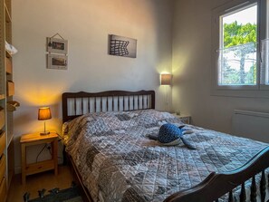 Ein Schlafzimmer mit einem Bett, Nachttischlampen, einem Fenster und Wanddekorationen.