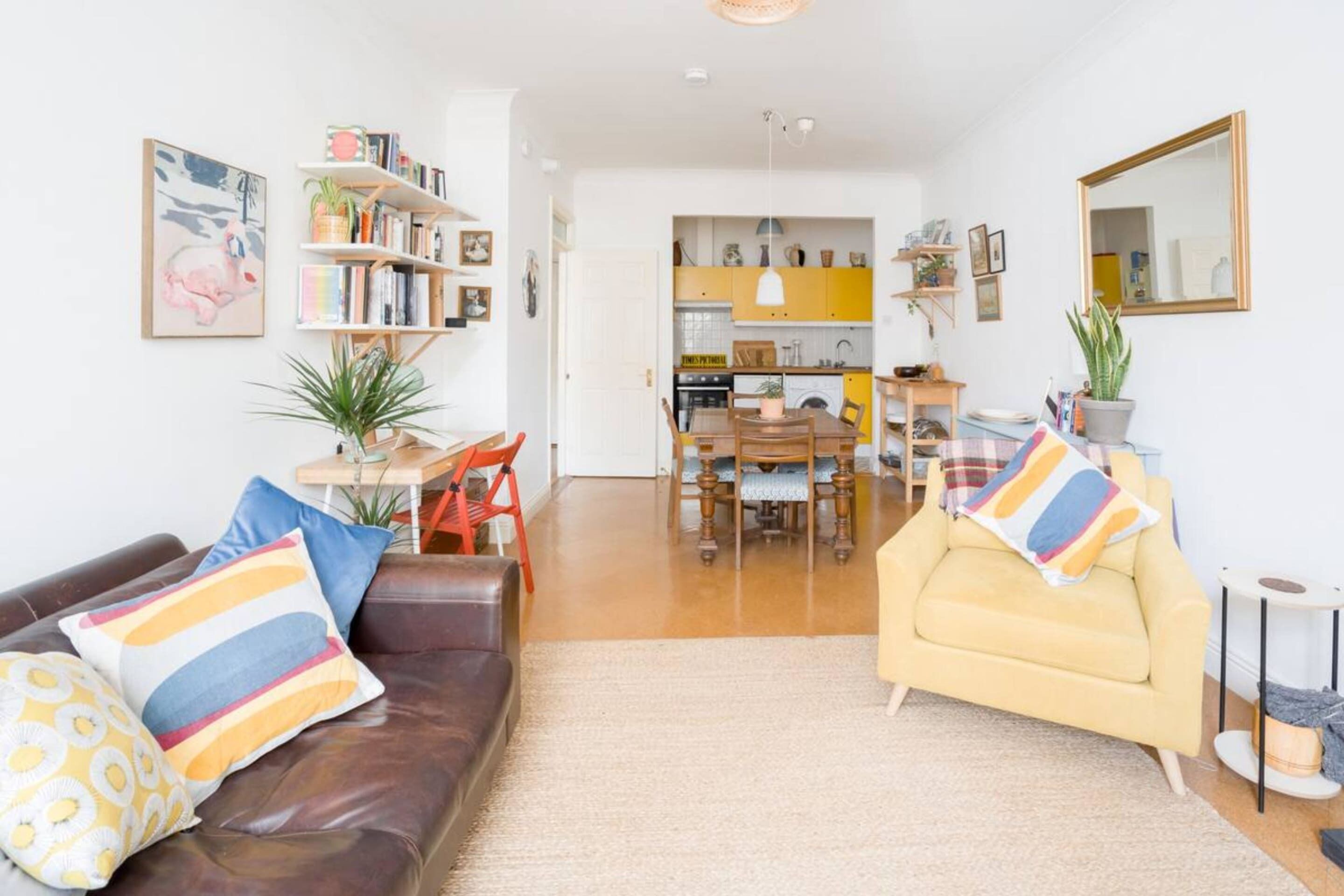 A living room with a brown leather sofa, a yellow armchair, and a dining area with a table and chairs.