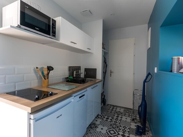 Una cocina compacta con microondas, lavavajillas y fregadero.