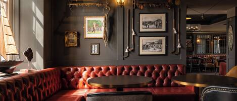 A cozy lounge area with a red leather sofa, a round table, and a grey armchair.