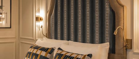 A neatly made bed with a patterned headboard, a bedside lamp, and a framed picture on the wall.