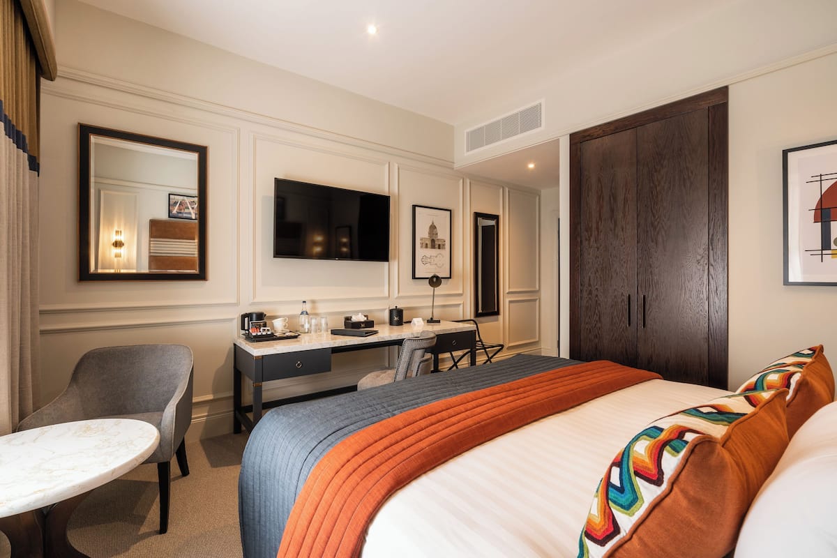 Une chambre d’hôtel avec un lit, un bureau, une chaise et un téléviseur.