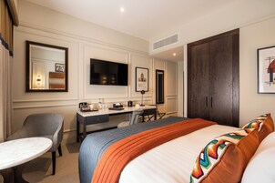 Una habitación de hotel con cama, escritorio, silla y televisor.