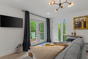 Una sala de estar moderna con un sofá gris, un televisor de pantalla plana y un comedor con mesa y sillas.