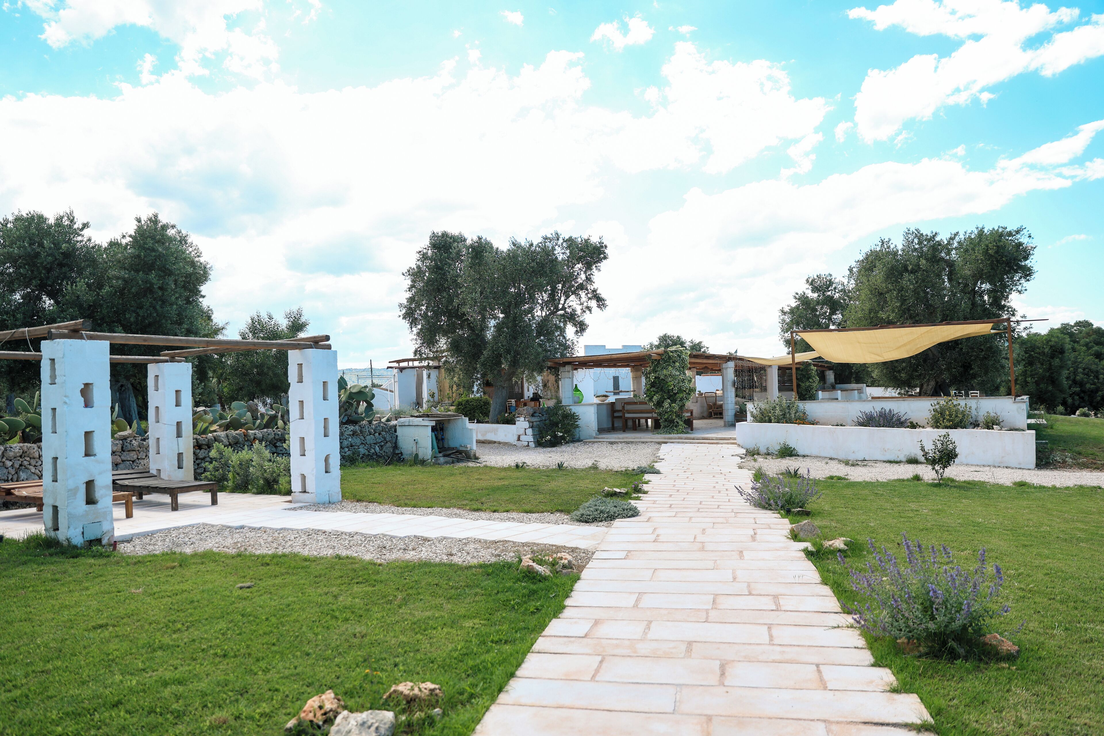 A garden pathway leading to a gazebo with a pergola overhead.