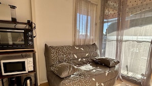 A cozy living area with a sofa, two microwaves, and a coffee maker on a wooden shelf. - Cozy Studio for 4 with A/C, Pools & Parking - 400m from Beach, 800m to Town Centre (Argelès-sur-Mer)