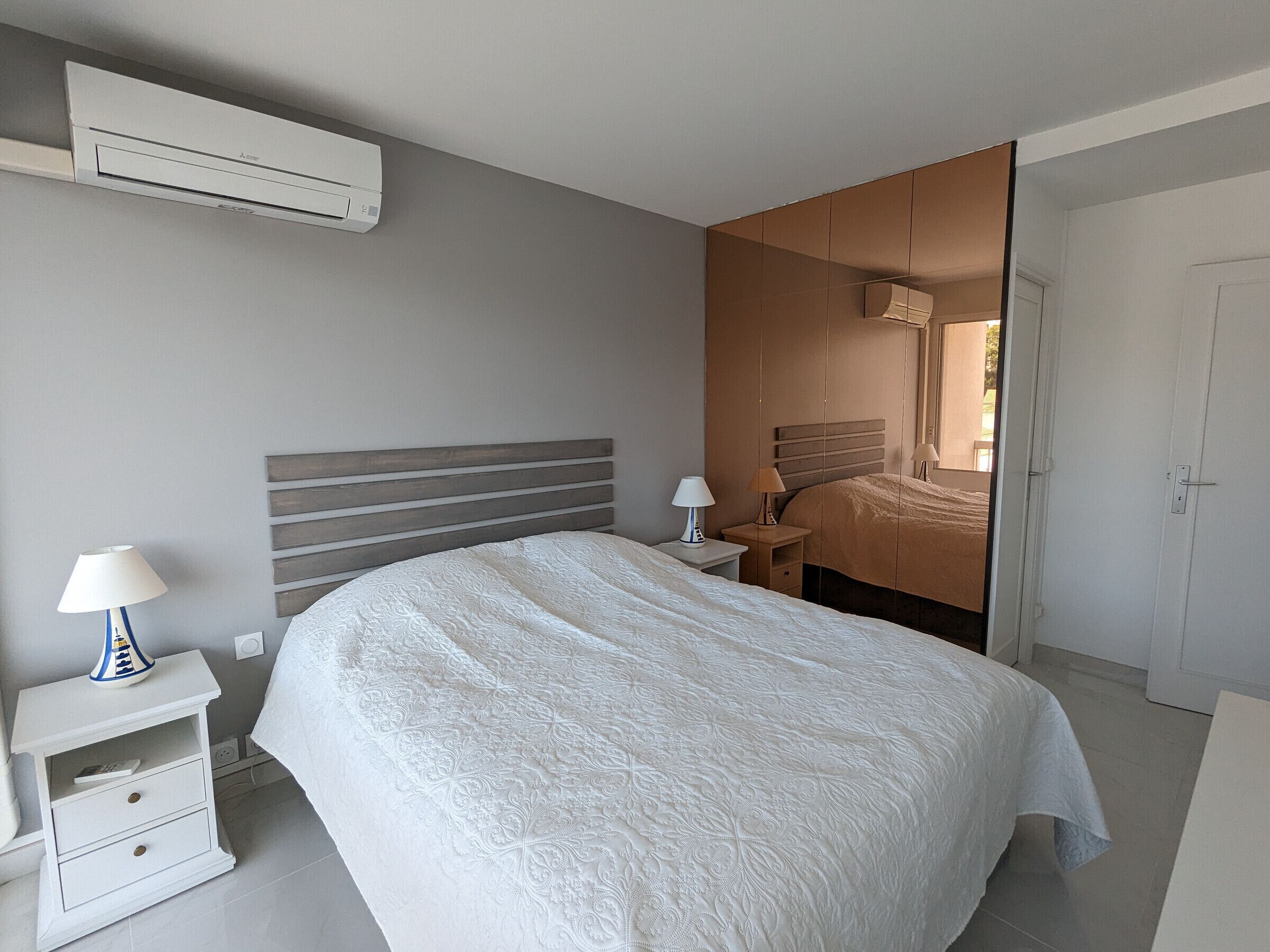 A bedroom with a large bed, a nightstand, a lamp, and a wardrobe.