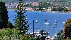 A coastal town with boats docked along the shore, surrounded by hills and buildings. - Georgias House Project First Floor (Skiathos)