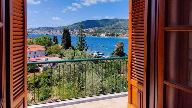A balcony with a view of a coastal town, greenery, and a clear sky. - Georgias House Project First Floor (Skiathos)